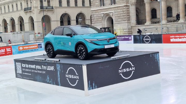 Auf einem Podest mit Nissan-Logo steht ein türkisblauer Nissan Leaf, das Podest steht auf der Eislaufbahn am Wiener Rathausplatz