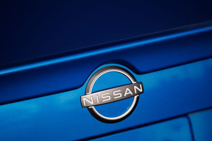 Close up of the Nissan badge on a blue Nissan trunk.