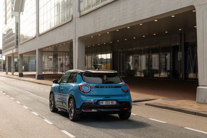Blick von schräg hinten auf einen blauen Nissan Micra, der im Abendlicht durch Rotterdam fährt