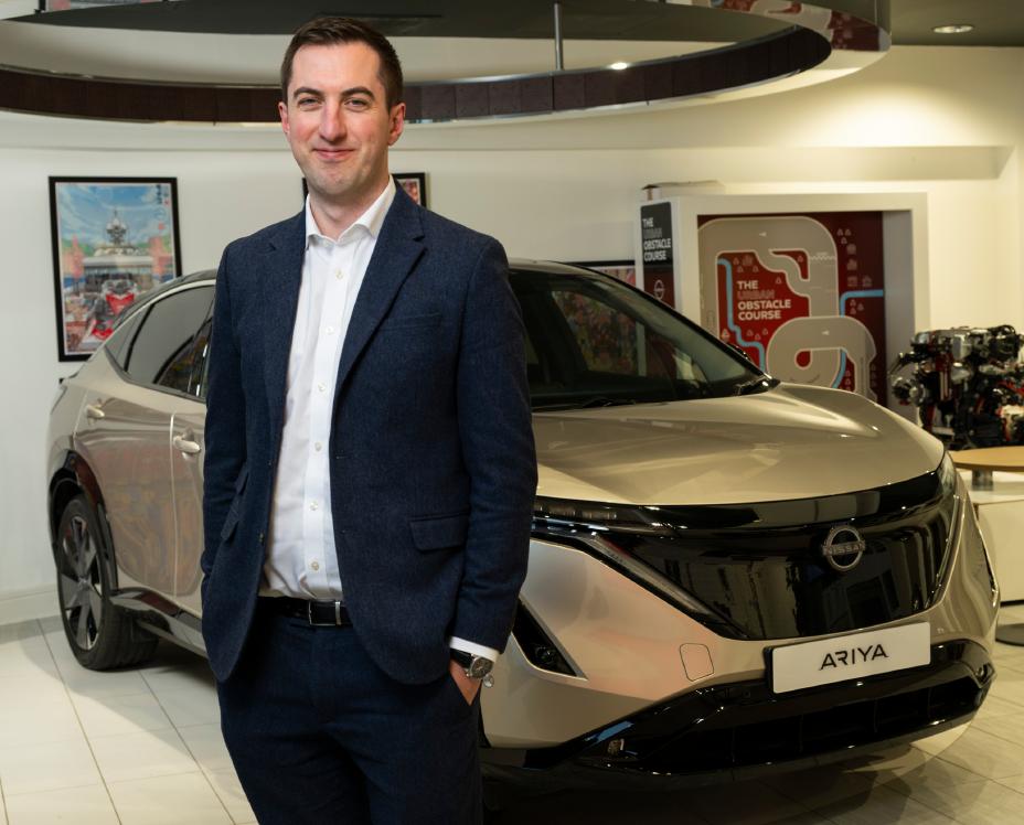 Matt Duncan standing in front of a silver Nissan Ariya electric vehicle.