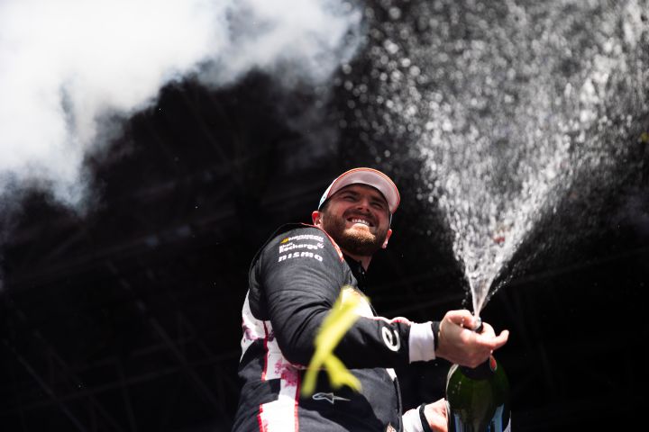 Oliver Rowland celebrates by spraying champagne on the Berlin podium