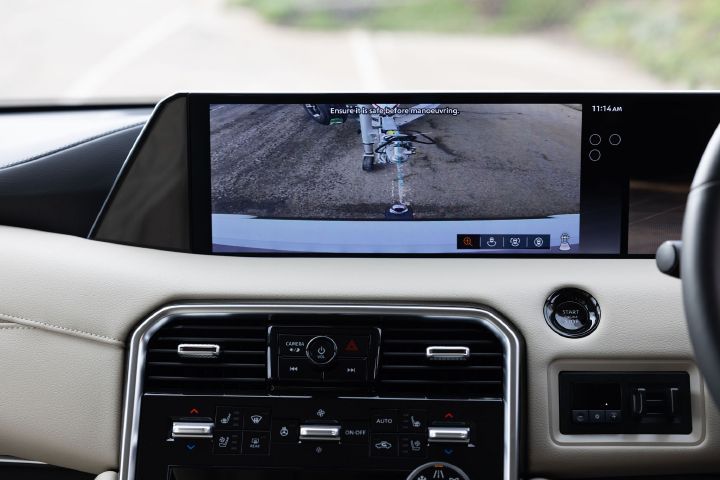 2026 Nissan Y63 Patrol finished in white, interior close-up showing the infotainment display with a rear camera view and guidance line aligned with a boat trailer hitch.