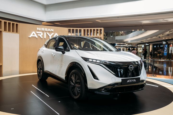 A white-color Nissan Ariya displayed in front of Nissan Ariya backdrop