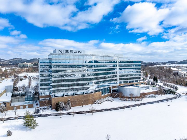 Back of NNA headquarters building and property, snow covers the ground and trees, the sky is bright blue.