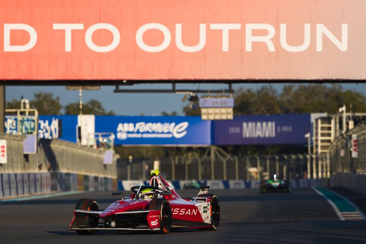 Oliver Rowland im Nissan e‑4ORCE 05 mit der Startnummer 1 biegt in Miami rechts in eine Kurve ein, über der Rennstrecke hängen blaue und rote Werbetafeln.