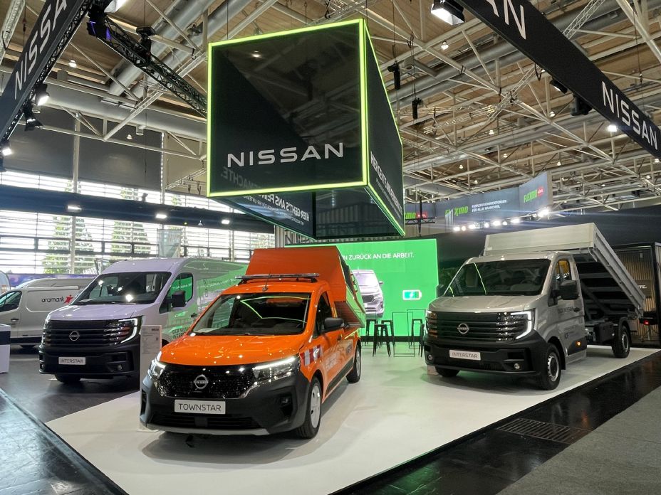 Auf dem Nissan Messestand auf der IAA Transportation steht im Vordergrund ein oranger Townstar EV im Sammelbehälter, daneben stehen Nissan Interstar mit verschiedenen Auf- und Umbauten
