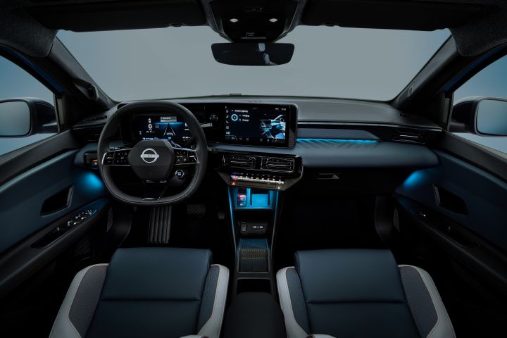 dimmed interior of Micra dashboard and cockpit from driver's POV revealing blue ambient lighting by side doors, on dashboard and below air conditioning buttons.  steering wheel, front seats and infotainment in view