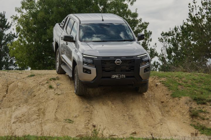 2026 Nissan Navara ST dual cab ute finished in Summit Silver captured head-on while descending a steep sandy off-road track.