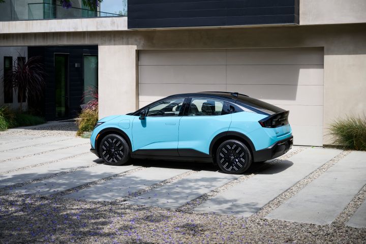 Profile view of a 2026 Nissan LEAF parked in front of a modern house during the daytime.
