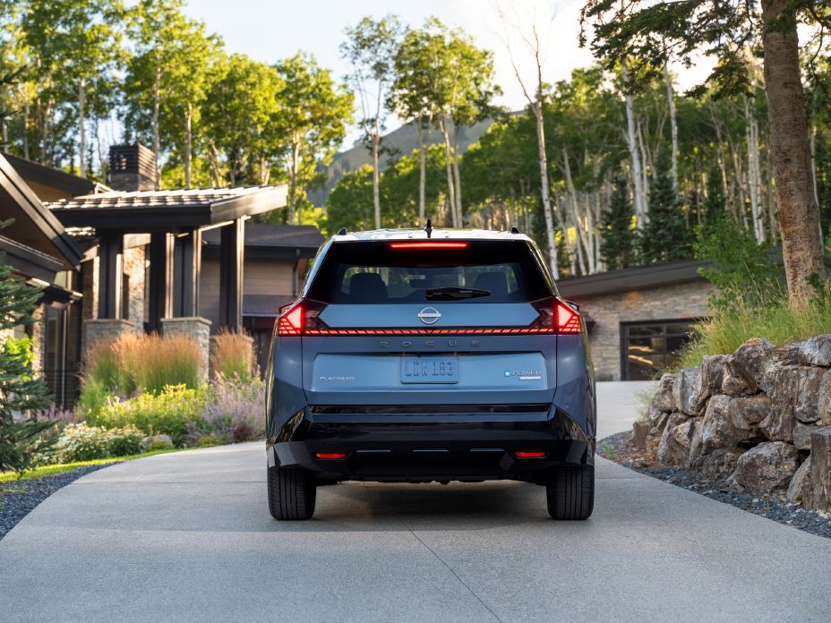 Rear view of the 2027 Nissan Rogue Hybrid Platinum parked in front of a house.