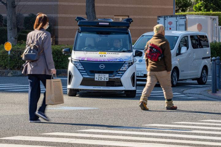 A scene where the experimental vehicle Serena is stopped at an intersection because pedestrians are crossing