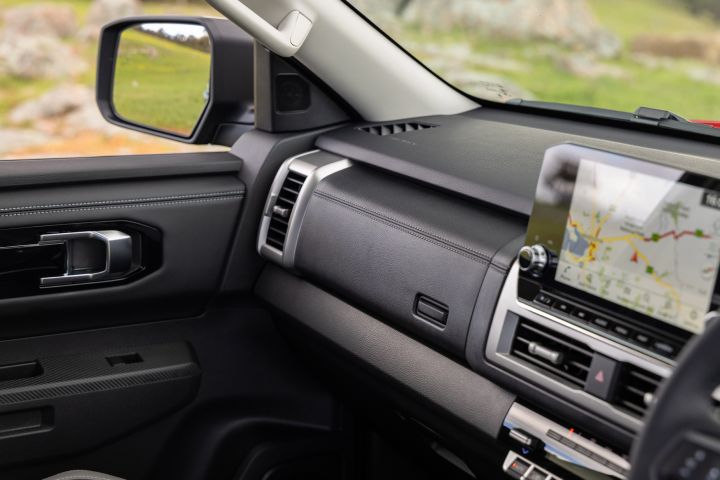 Passenger-side dashboard view of a 2026 Nissan Navara ST-X, showing the glovebox area, passenger door trim, side mirror, and part of the 9-inch Touch infotainment screen displaying a map.