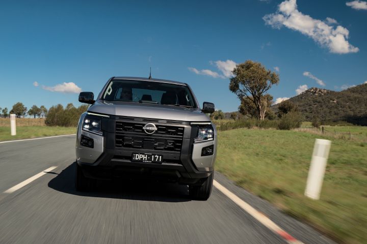 2026 Nissan Navara ST dual cab ute finished in Summit Silver captured head-on while driving along a tree-lined country road.