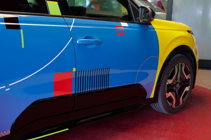 Detailaufnahme des Nissan Micra Signature Edition Gewinnerfahrzeugs, auf der rechten Seite mit markanten grafischen Mustern, ein gelber Block an der Fahrzeugfront und geometrische Linien auf der blauen Karosserie.