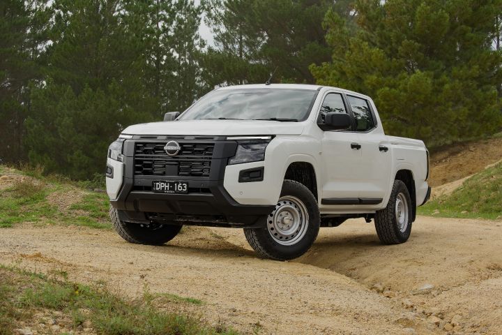 An angled image of an Alpine White 2026 Nissan Navara parked on dirt with a shallow ditch underneath