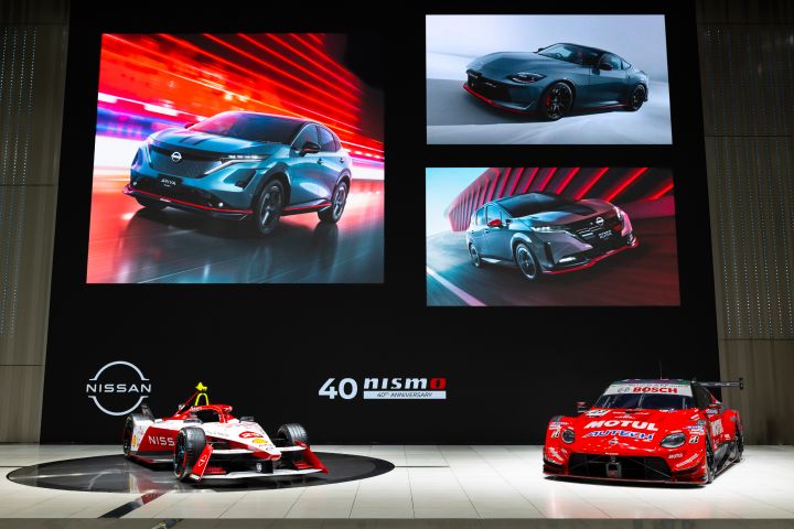 Samochód wyścigowy Nissana Formuły E i samochód GT500 na scenie z grafikami trzech samochodów produkcyjnych NISMO na ekranie z tyłu.