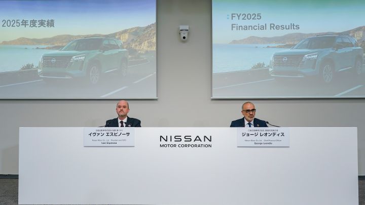 O presidente e CEO da Nissan Ivan Espinosa ao lado do CFO George Leondis em uma mesa branca com o logo da Nissan. Ao fundo, dois telões projetam fotos de carros