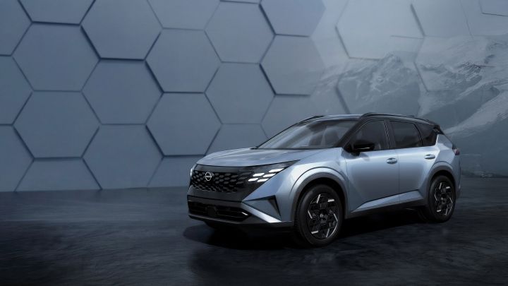 In a subdued setting with a geometric-patterned wall, a silver X‑Trail / Rogue is shown stationary, facing slightly forward at an angle.