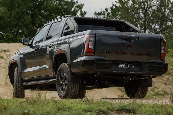 2026 Nissan Navara PRO-4X finished in Boulder Grey from a low rear three‑quarter angle, highlighting sculpted bumper, stacked tail‑lamps, sports bar and visible underbody hardware.