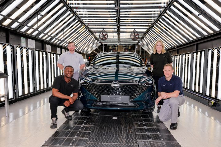 Neben einem dunkelgrünen Nissan Qashqai neuer Generation knien zwei Nissan Mitarbeiter, hinter ihnen stehen zwei weitere