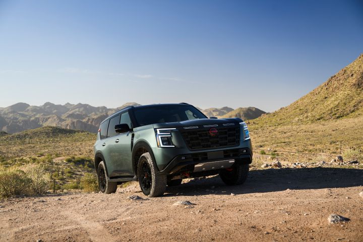 A 2025 Nissan Armada PRO-4X parked at a steep angle on a rocky hill, a cloudless sky is behind.