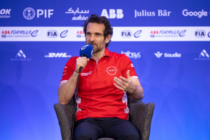 Tommaso Volpe, Geschäftsführer und Teamchef des Nissan Formula E Teams, trägt sein rotes Team-Poloshirt und hält ein Mikrofon in der rechten Hand, während er Fragen der Medien beantwortet.