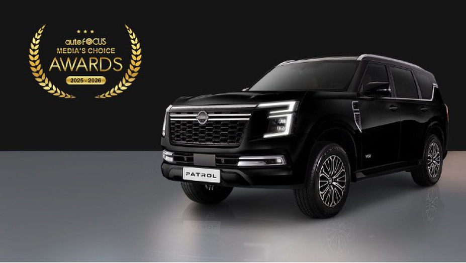 A black Nissan Patrol SUV displayed on a reflective surface with a dark background, positioned to the right. To the left is a gold laurel emblem showing the AutoFocus Media’s Choice Awards 2025–2026.