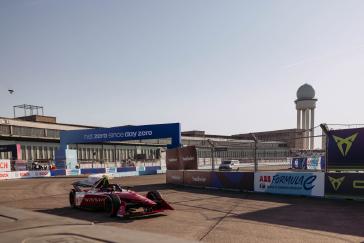 Formula E racer driving from left to right of camera on dirt track