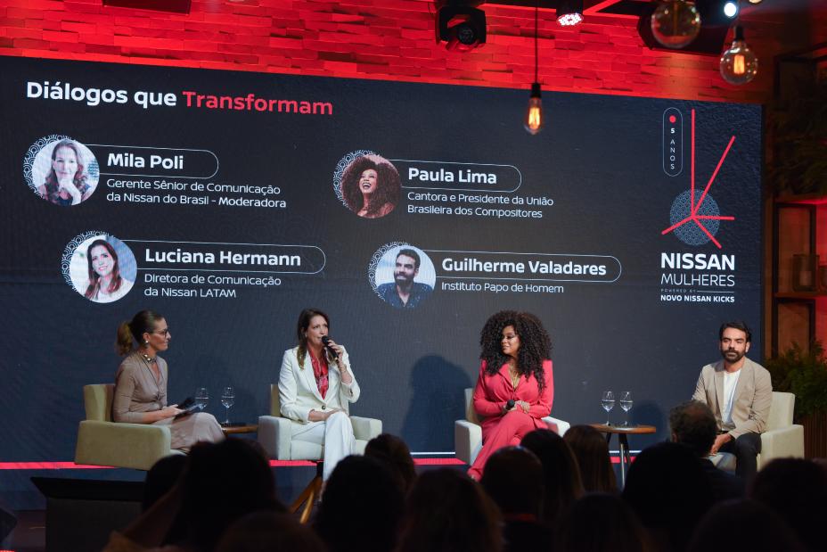Quatro pessoas sentadas em um palco à frente de um painel com os nomes e Diálogos que Transformam escrito em vermelho