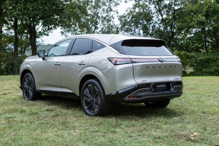 Left rear 3/4 angle of a silver 2025 Nissan Murano parked on grass with trees behind.