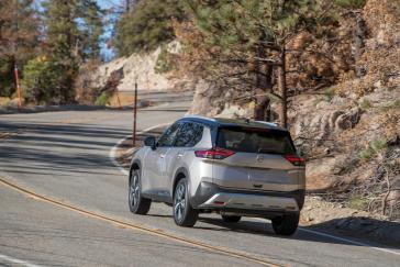 Rear view of the 2022 Nissan Rogue driving down a curved road.