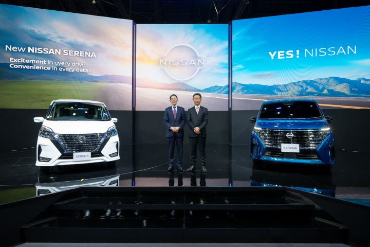 Two Nissan Executives standing on the stage between a white Nissan Serena and a blue Nissan Serena