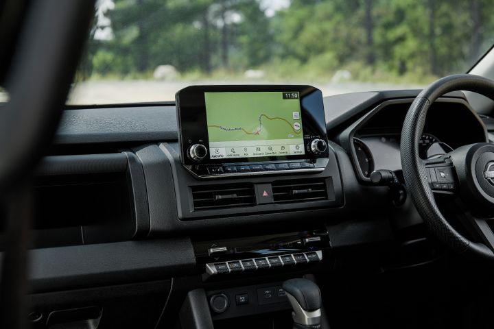 2026 Nissan Navara SL dual cab ute finished in Alpine White with a close interior view of the navigation touchscreen, centre vents and part of the right-hand-drive dashboard.