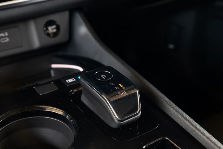 Close-up of the Nissan X‑Trail centre console, featuring the electronic gear selector, cup holder and surrounding controls.