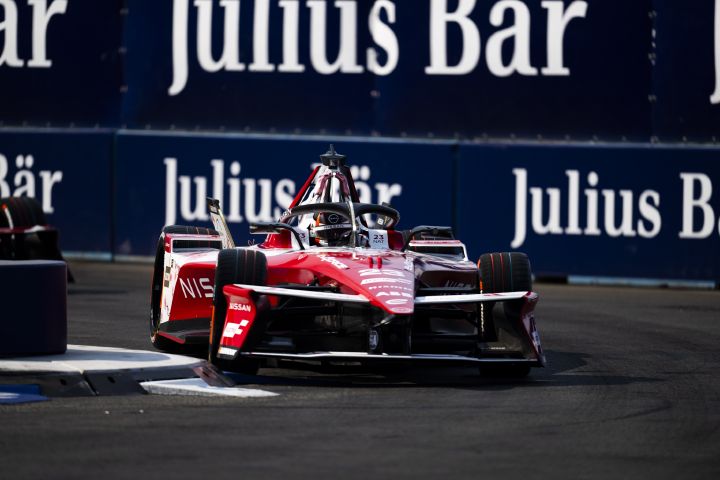 Norman Nato fährt in seinem Nissan Formel-E-Rennwagen durch eine Rechtskurve und ist dabei nach rechts ausgerichtet. Im Hintergrund ist eine dunkelblaue Wand mit weißer Beschilderung zu sehen.