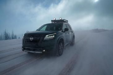 A black 2022 Nissan Pathfinder is driving down a snowy road.