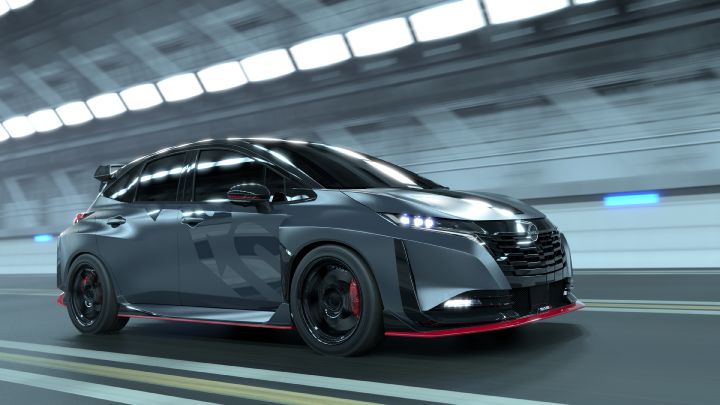 A silver and black two-tone sports car, the Aura Nismo RS Concept, speeding through a tunnel in a full side view. The vehicle features a low stance and a large rear wing, with black wheels and visible red brake calipers. The side displays a light gray 'RS,' and a red accent line runs along the lower body. The tunnel walls appear blurred in the background, emphasizing motion and dynamic speed