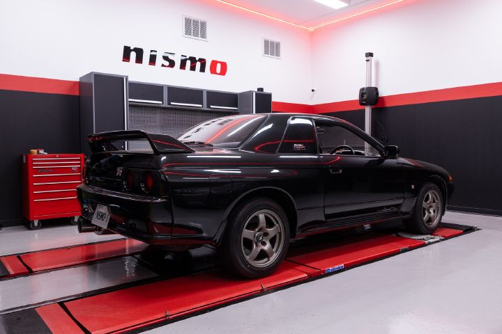 An R32 GT‑R in the workshop of the new NISMO Performance Centre Melbourne with red hoist below.