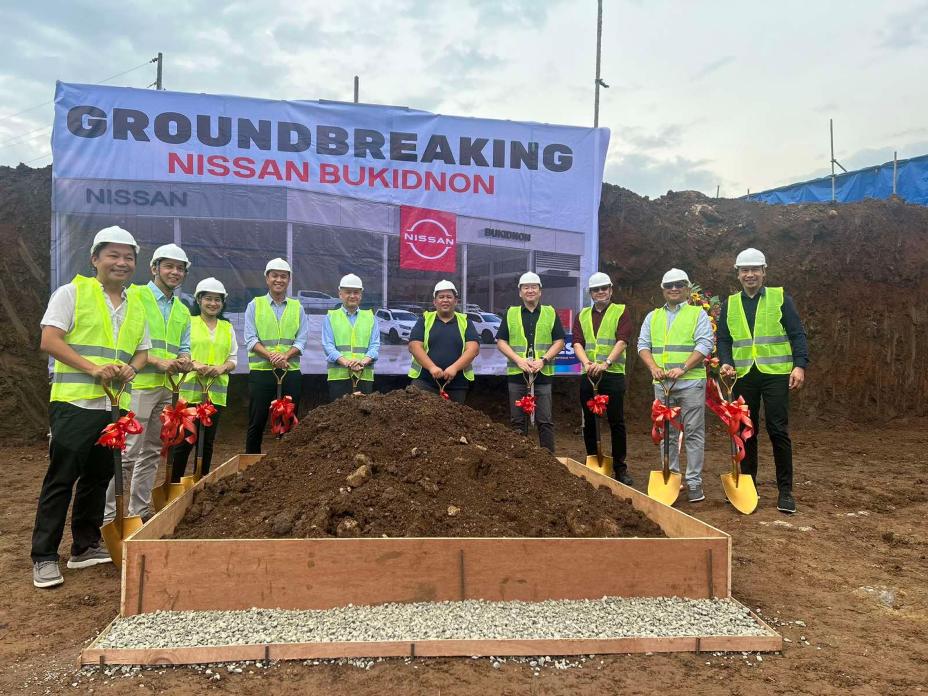 A group of people in safety vests and helmets standing in front of a pile of soil.