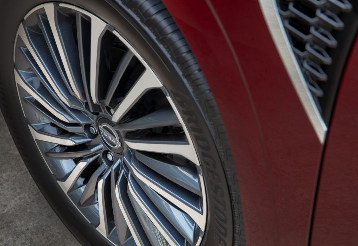 Angled close up of the tire and silver rim that features a Nissan logo in the center on a red 2025 Nissan Armada.