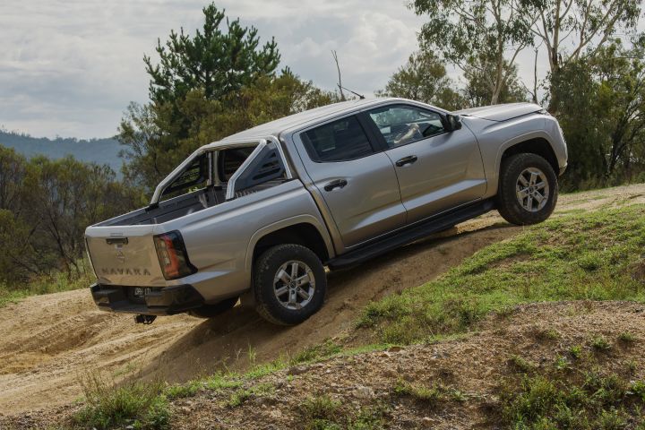 2026 Nissan Navara ST dual cab ute finished in Summit Silver shown from the rear-left ascending a sandy hillside track.