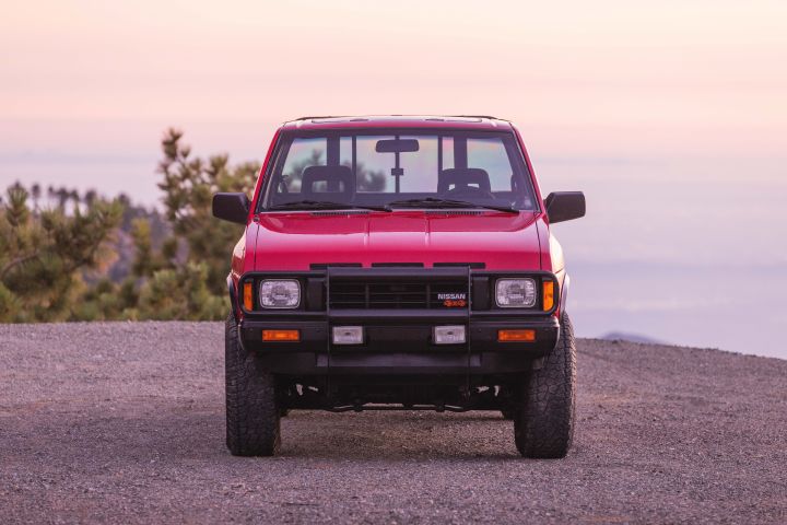 Front view of a red 1990 Nissan Hardbody 4x4 parked on asphalt.