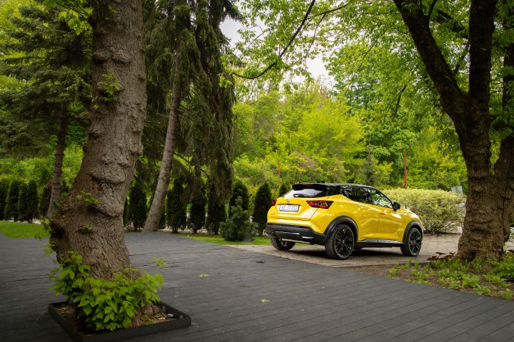 Stojący żółty Nissan Juke (widok z boku) na tle zieleni