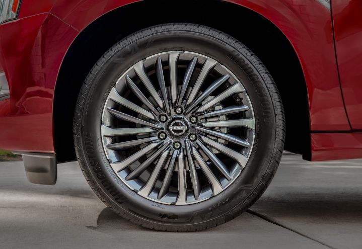 Close up of the tire and silver rim that features a Nissan logo in the center on a red 2025 Nissan Armada.