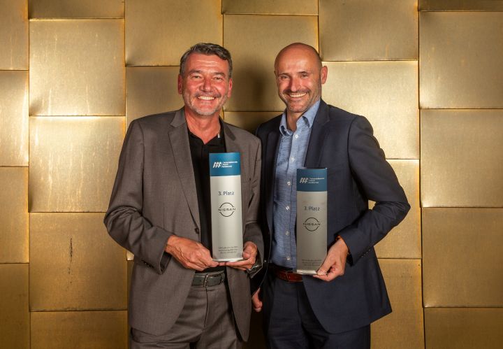 Martin Huber und Pascal Michaeli stehen vor einer goldenen Wand und lächeln mit den Trophäen in der Hand in die Kamera