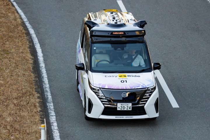 A scene capturing the experimental vehicle "Serena" driving through the streets of Yokohama. The scene is captured from the left side.