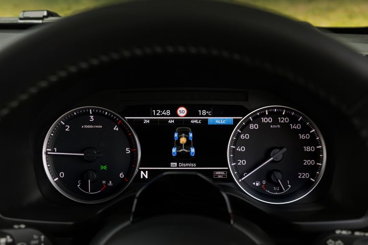 2026 Nissan Navara PRO-4X finished in Boulder Grey highlighting the driver display with 4LLC engaged, axle illustration and flanking analogue gauges.