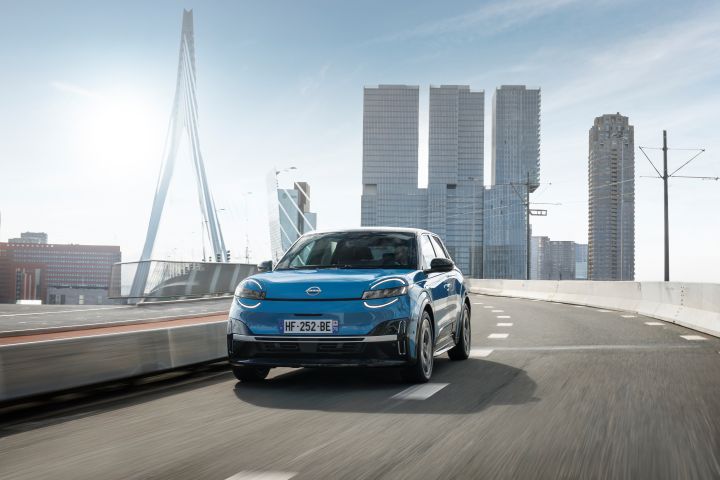 Fahraufnahme eines blauen Nissan Micra auf einer Brücke im Zentrum von Rotterdam vor drei Hochhäusern