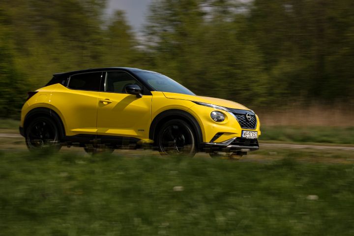 Jadący żółty Nissan Juke (widok z boku) na tle zieleni