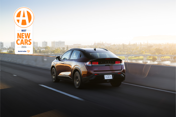 A red Nissan LEAF drives on a bridge as the sun sets.